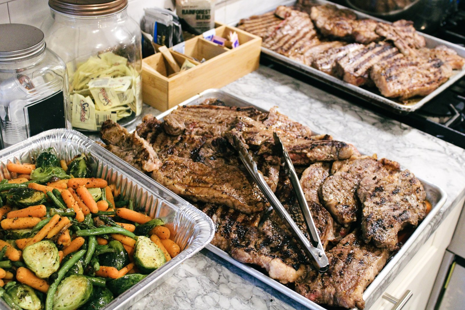 Catering trays of grilled steaks and roasted vegetables ready for service