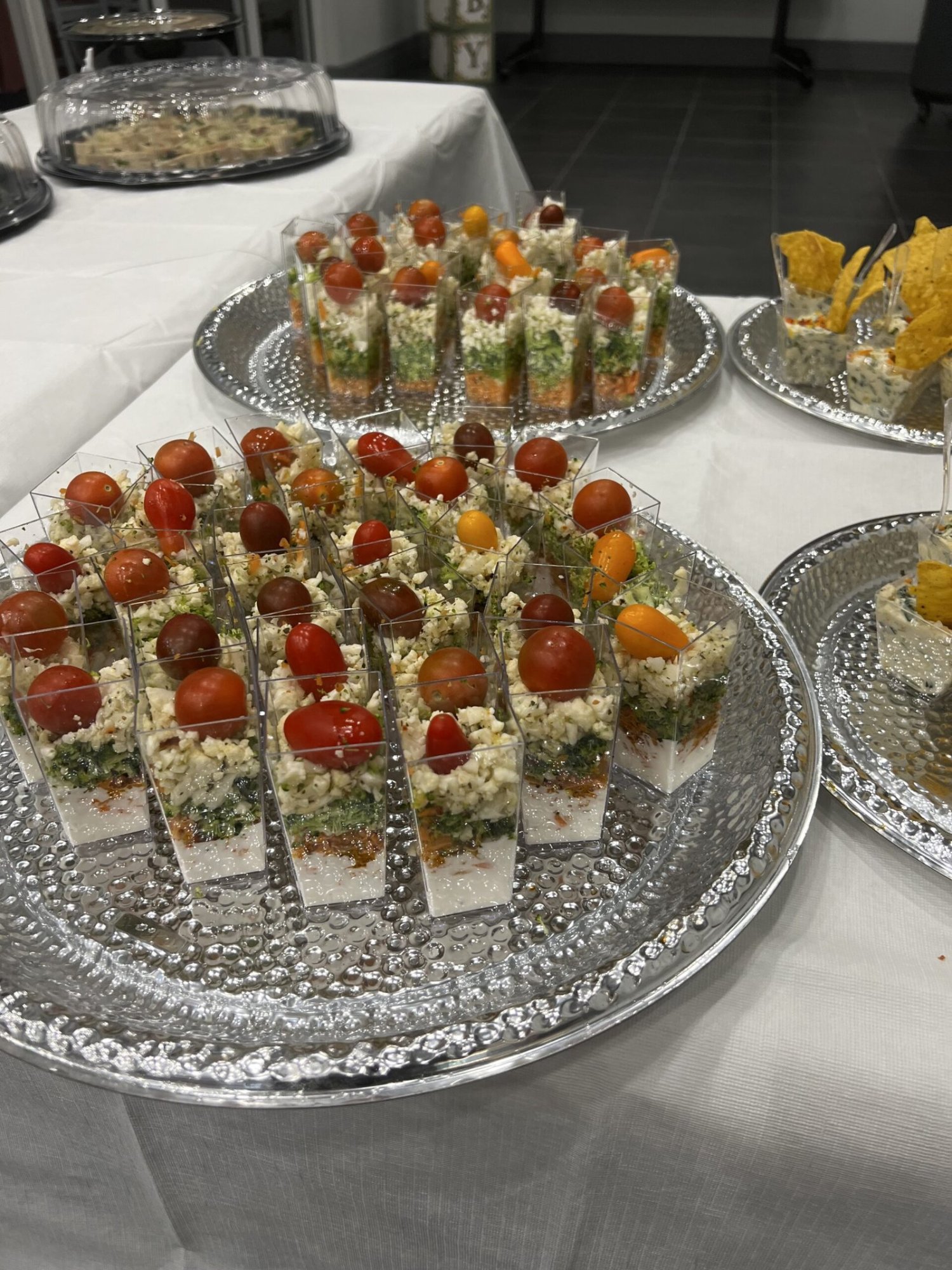 Layered appetizer cups lined up on silver catering trays